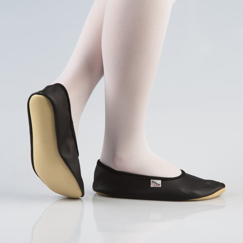 1. Women's black leather gymnastics slippers with rubber sole, shown in side view on model wearing white tights