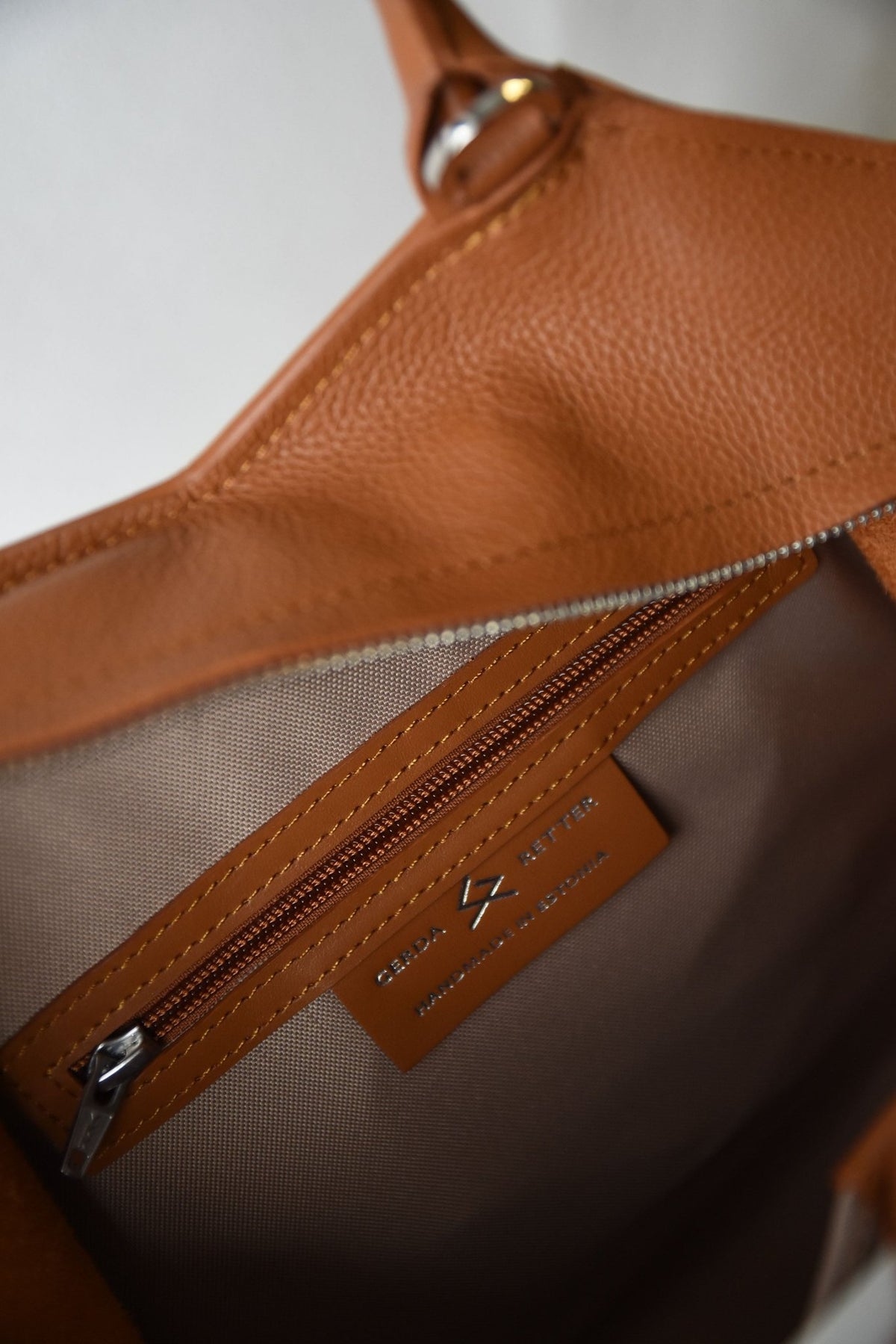 4. Woman holding Gerda Retter Design Leather Handbag Nova in black, styled with a green dress, against a concrete wall