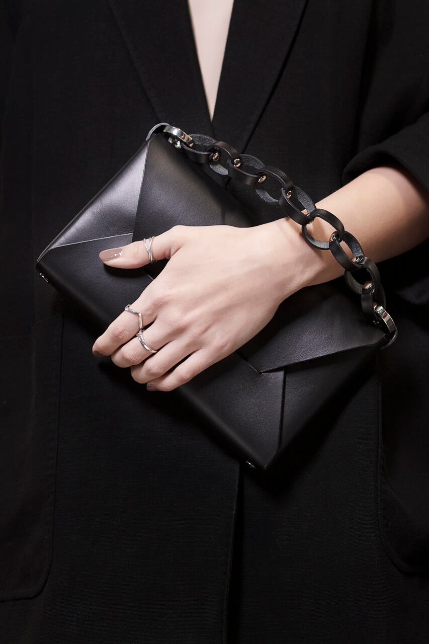 6. Black Stella Soomlais Wine & Dine evening bag held by person in black outfit with chunky chain strap