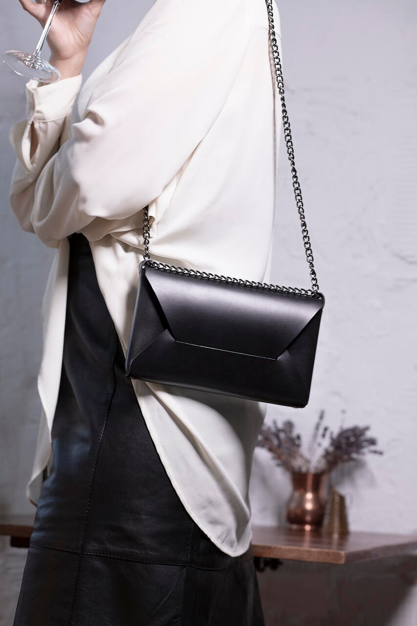 5. Woman in white blouse and black skirt wearing black Stella Soomlais Wine & Dine evening bag with chain strap