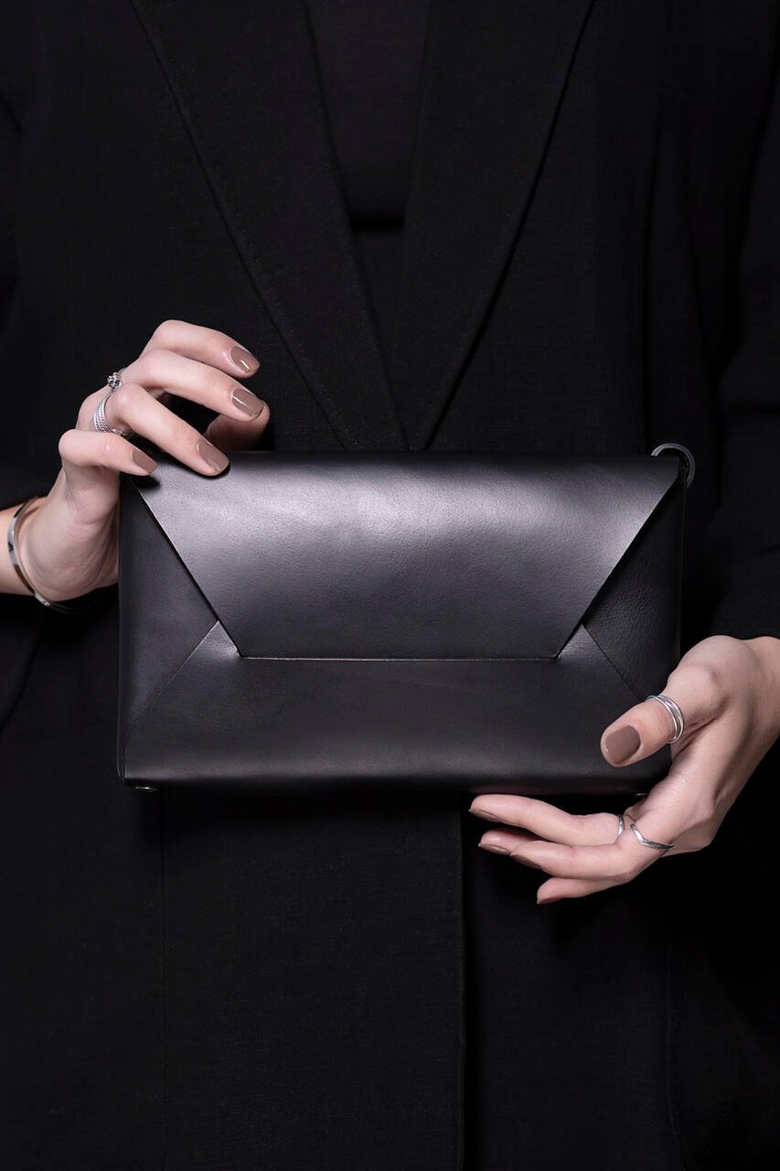 3. Black Stella Soomlais Wine & Dine evening bag held by person in black outfit, highlighting minimalist design