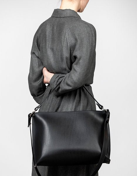 4. Woman in grey coat holding Stella Soomlais black leather handbag, emphasizing its size and elegant style.