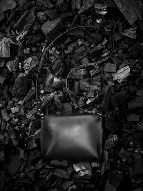 2. Black leather Stella Soomlais handbag with adjustable strap on textured dark background
