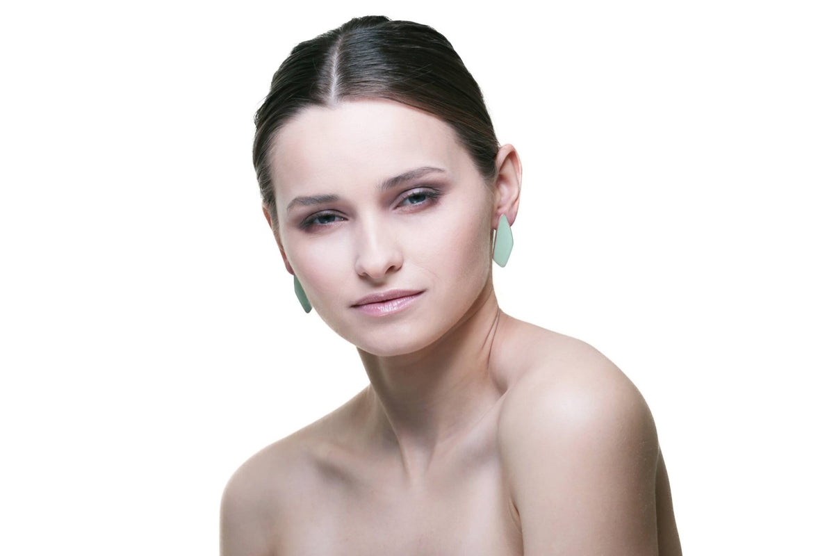 1. Woman wearing Lisa Kroeber Jewellery Leaves Small Earrings in white, showcasing elegant design