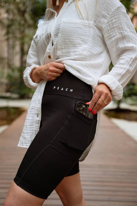 3. Close-up of Peachlabel black biker shorts with signature pocket holding a phone