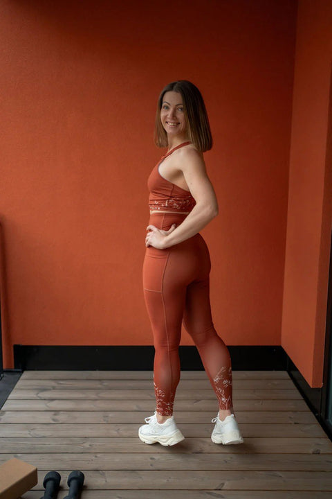 5. Woman in Peachlabel 'Wildflowers' brown leggings, side view showing fit and floral pattern on a wooden deck