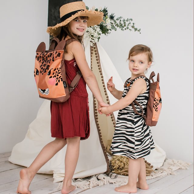 1. Two girls wearing Muni kids leopard backpacks, showcasing playful design in lifestyle setting