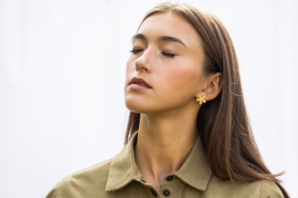 1. Woman wearing Lentsius Sunlit gold-tone flower earrings, eyes closed in peaceful pose