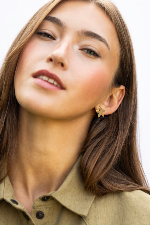 1. Woman wearing Lentsius Sunlit gold-tone flower earrings, tilting head slightly with relaxed expression