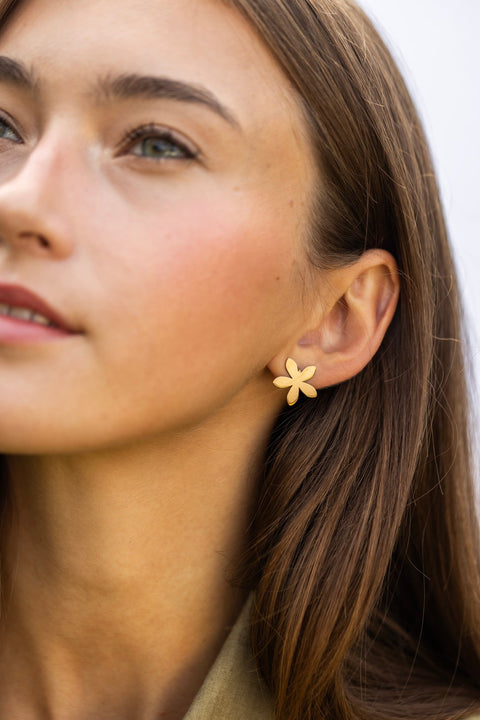1. Woman wearing Lentsius Sunlit gold-tone flower earrings, looking upwards with soft expression