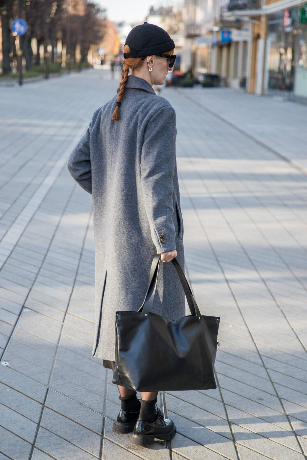2. Woman in urban setting carrying PYKOK Large Handbag Lima in soft black leather, emphasizing chic and functional style