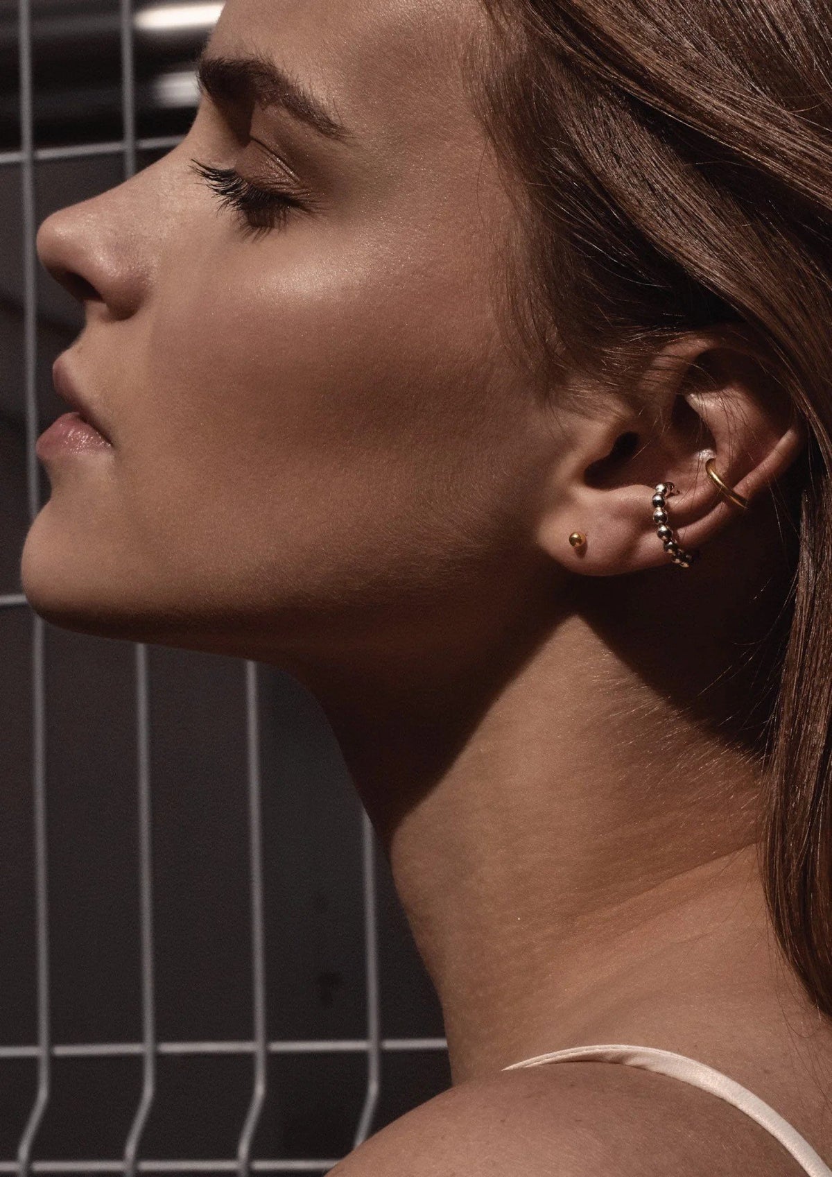 4. Women's gold Line Ear Cuff by NO MORE, worn with additional earrings, shown in lifestyle setting