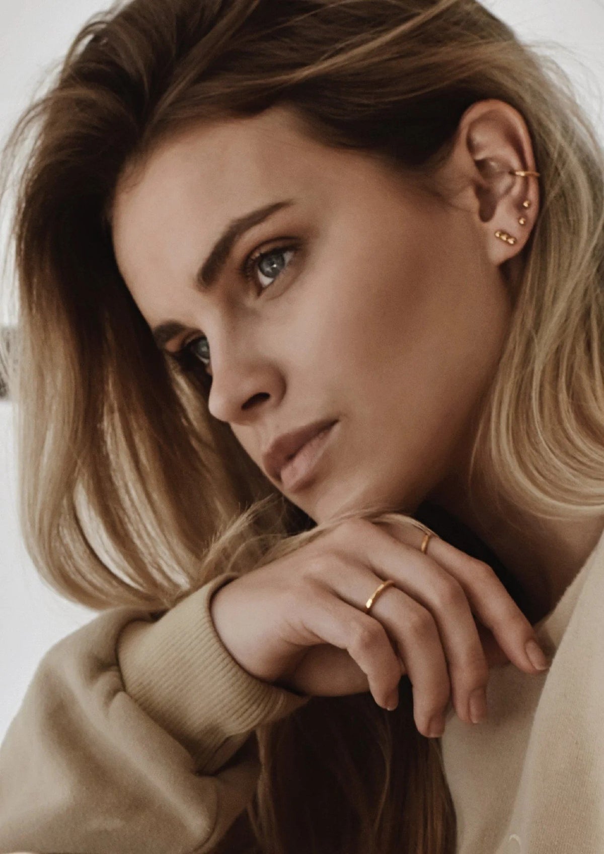 1. Women's gold Line Ear Cuff by NO MORE, styled with multiple earrings, shown in lifestyle setting