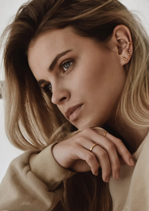 1. Women's gold Line Ear Cuff by NO MORE, styled with multiple earrings, shown in lifestyle setting