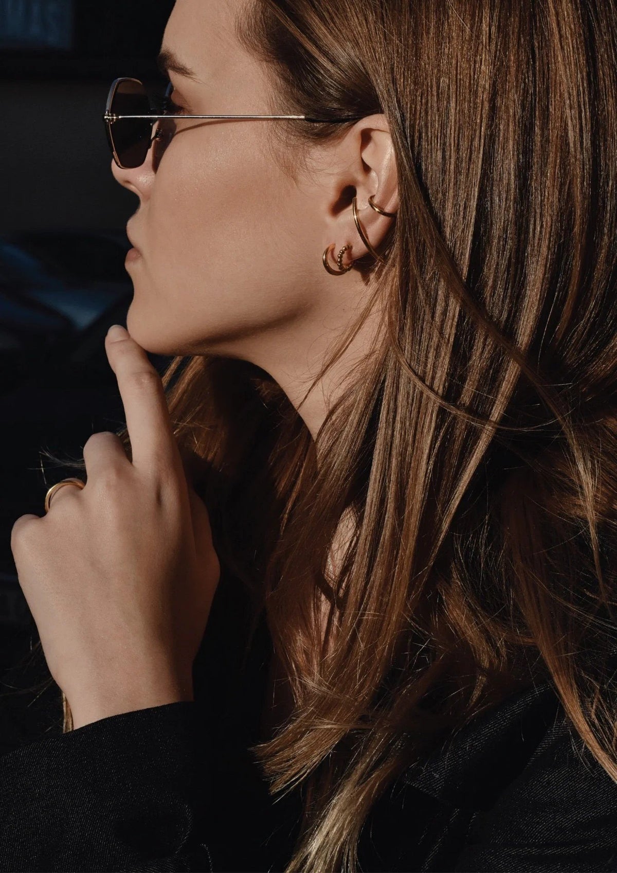 2. Women's gold Line Ear Cuff by NO MORE, worn with sunglasses, shown in lifestyle setting