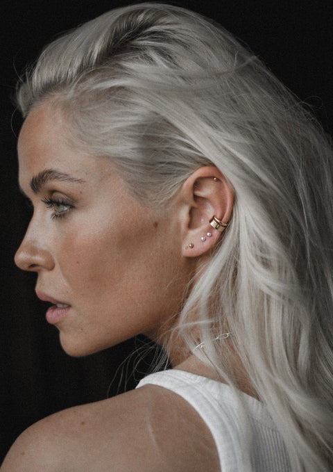 3. Women's gold Line Ear Cuff by NO MORE, styled with multiple piercings, shown in lifestyle setting