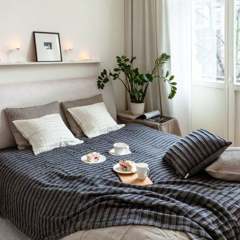 1. Black and gray linen-cotton bedcover on a bed in a cozy bedroom with pillows, plants, and breakfast setup