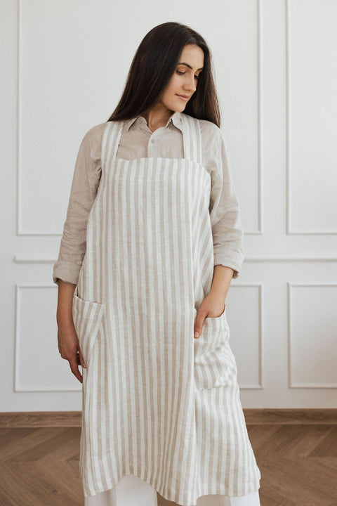 4. Woman in striped linen apron with hands in pockets, standing in a bright room