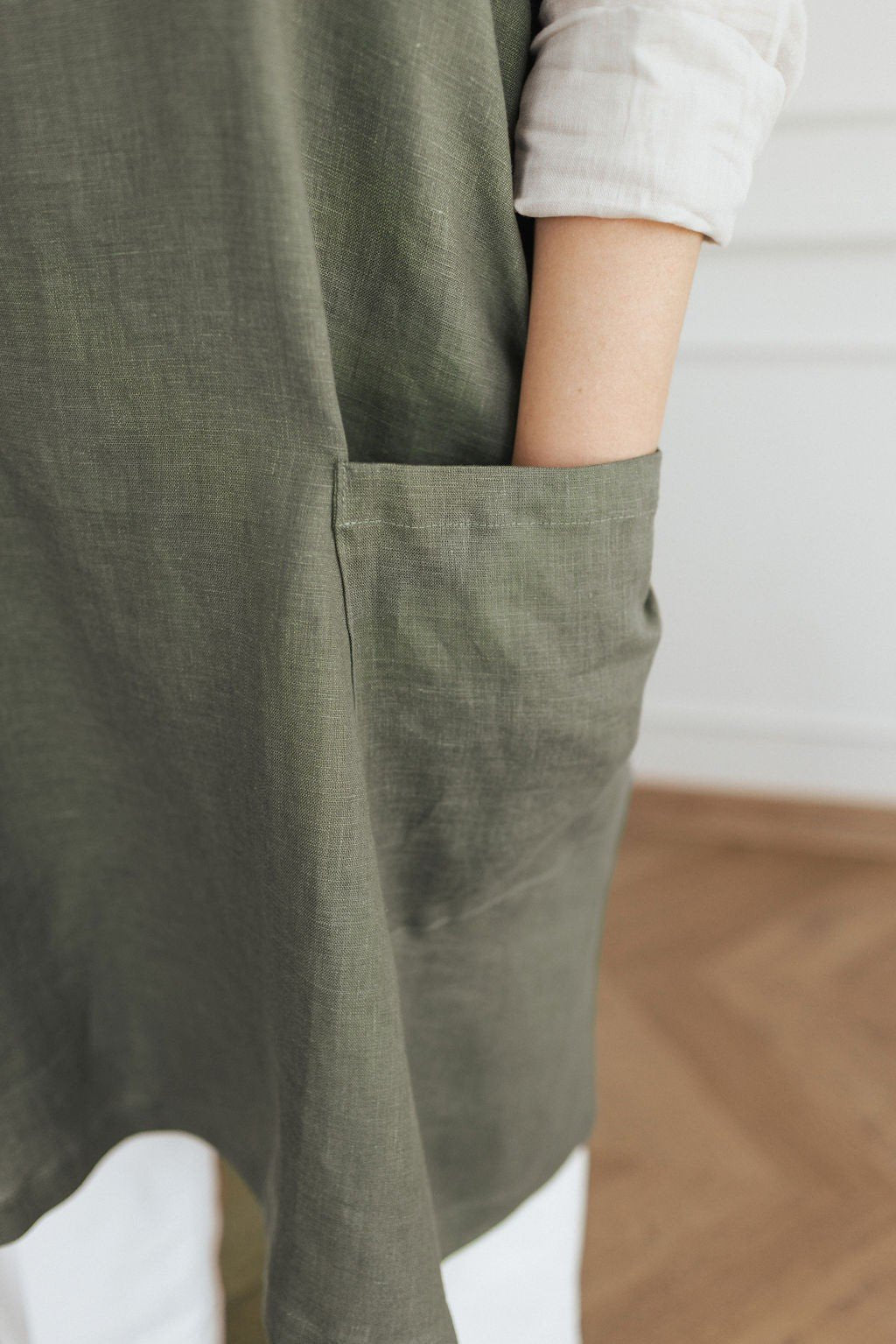 8. Close-up of olive green linen apron pocket with hand inside