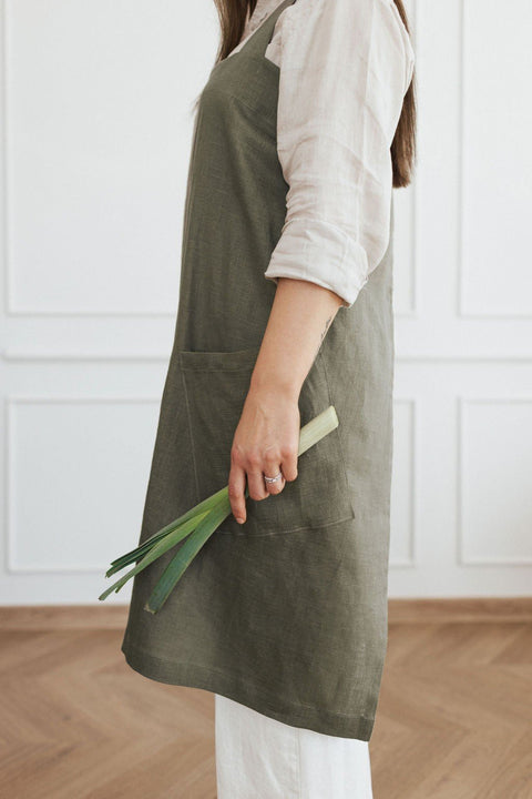 5. Side view of woman in olive green linen apron holding green onions