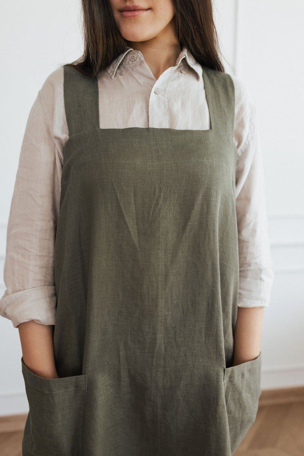 7. Front view of woman in olive green linen apron with spacious pockets