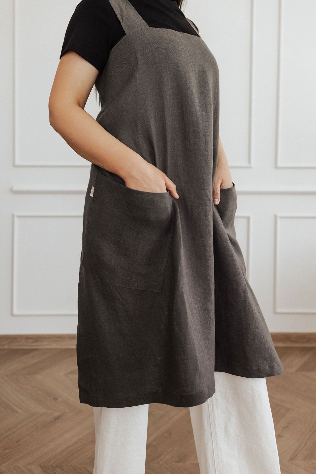 12. Side view of dark grey linen apron with hands in pockets