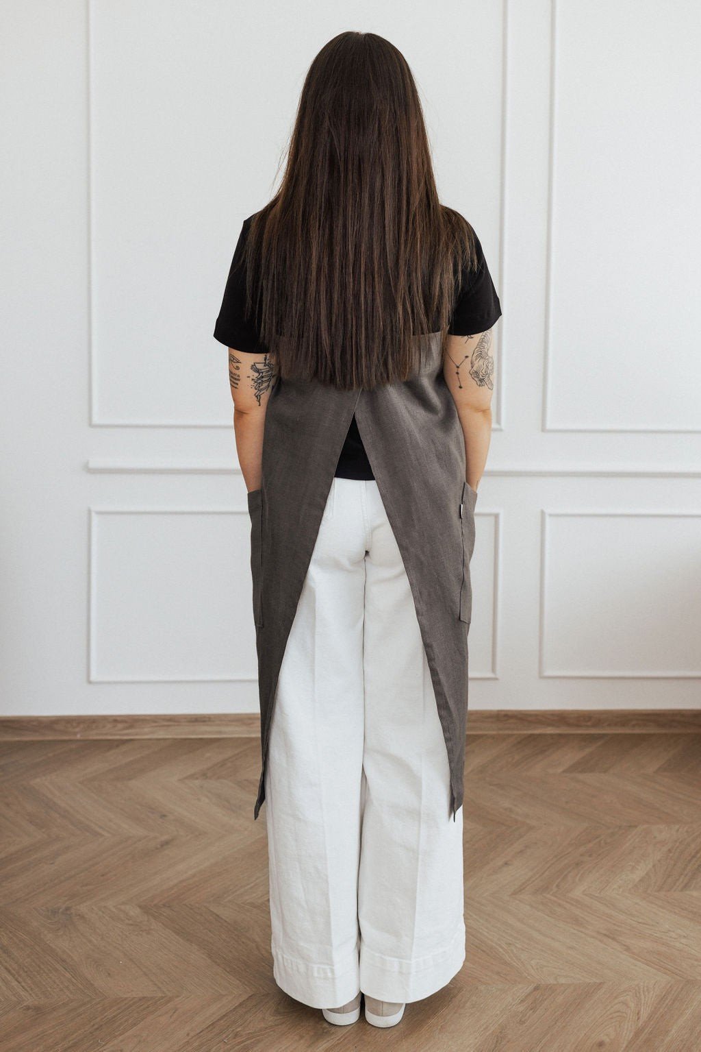 13. Back view of woman in dark grey linen apron with crossed straps