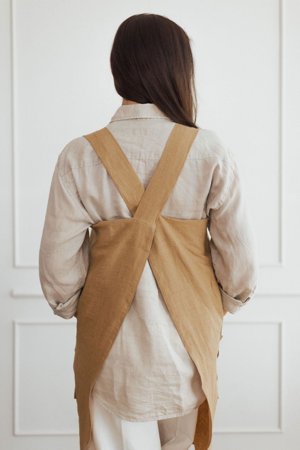 14. Back view of woman in beige linen apron with crossed straps