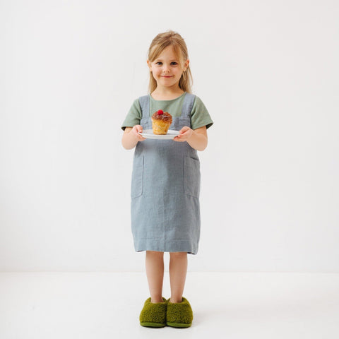 4. Girl holding a plate with a muffin, wearing blue fog linen apron and green slippers