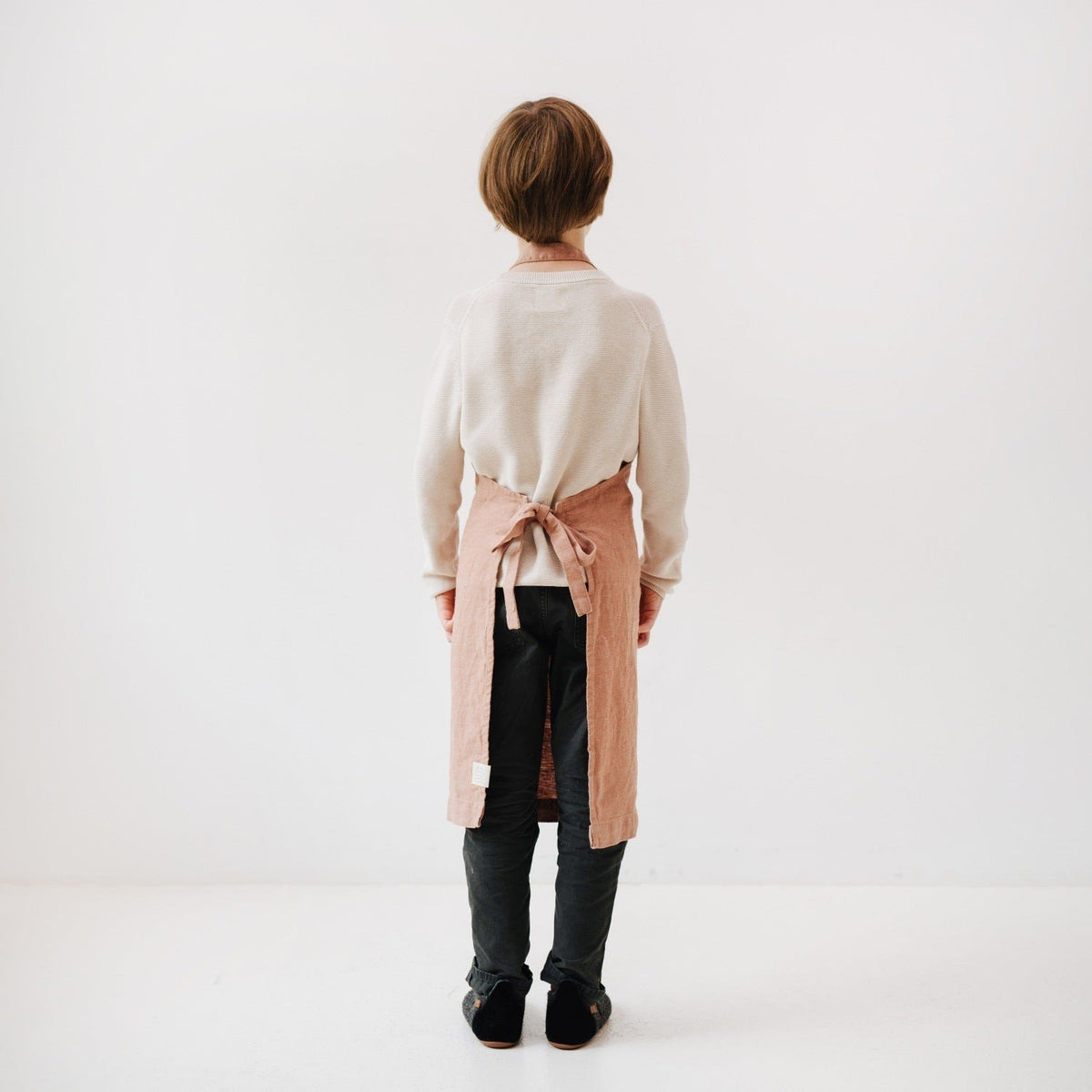 6. Back view of child in cafe creme linen apron showing tie closure