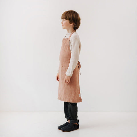 5. Side view of child in cafe creme linen apron with adjustable tie closure