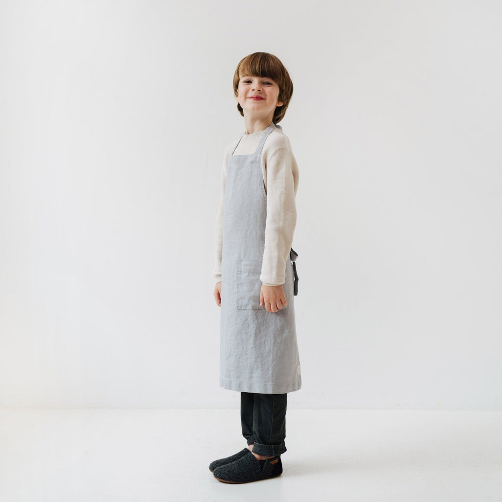 5. Child smiling in light grey linen apron with front pocket