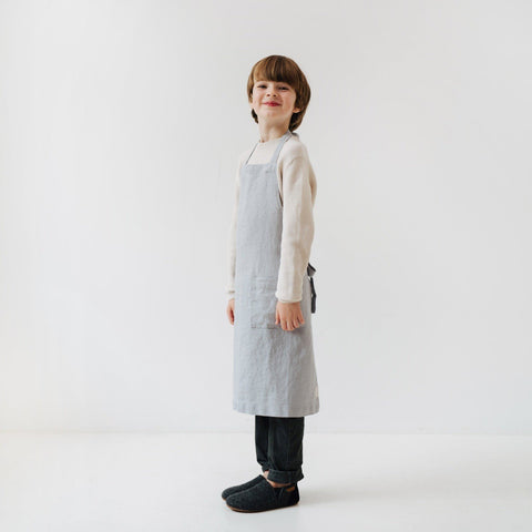 5. Child smiling in light grey linen apron with front pocket