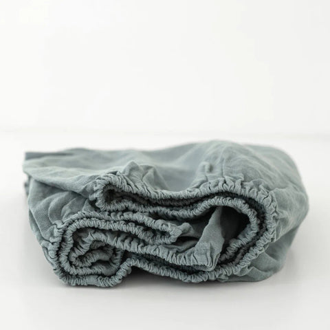 2. Blue fog linen fitted sheet for kids with elastic hem, folded on a white background, highlighting soft and durable fabric by Linen Tales.