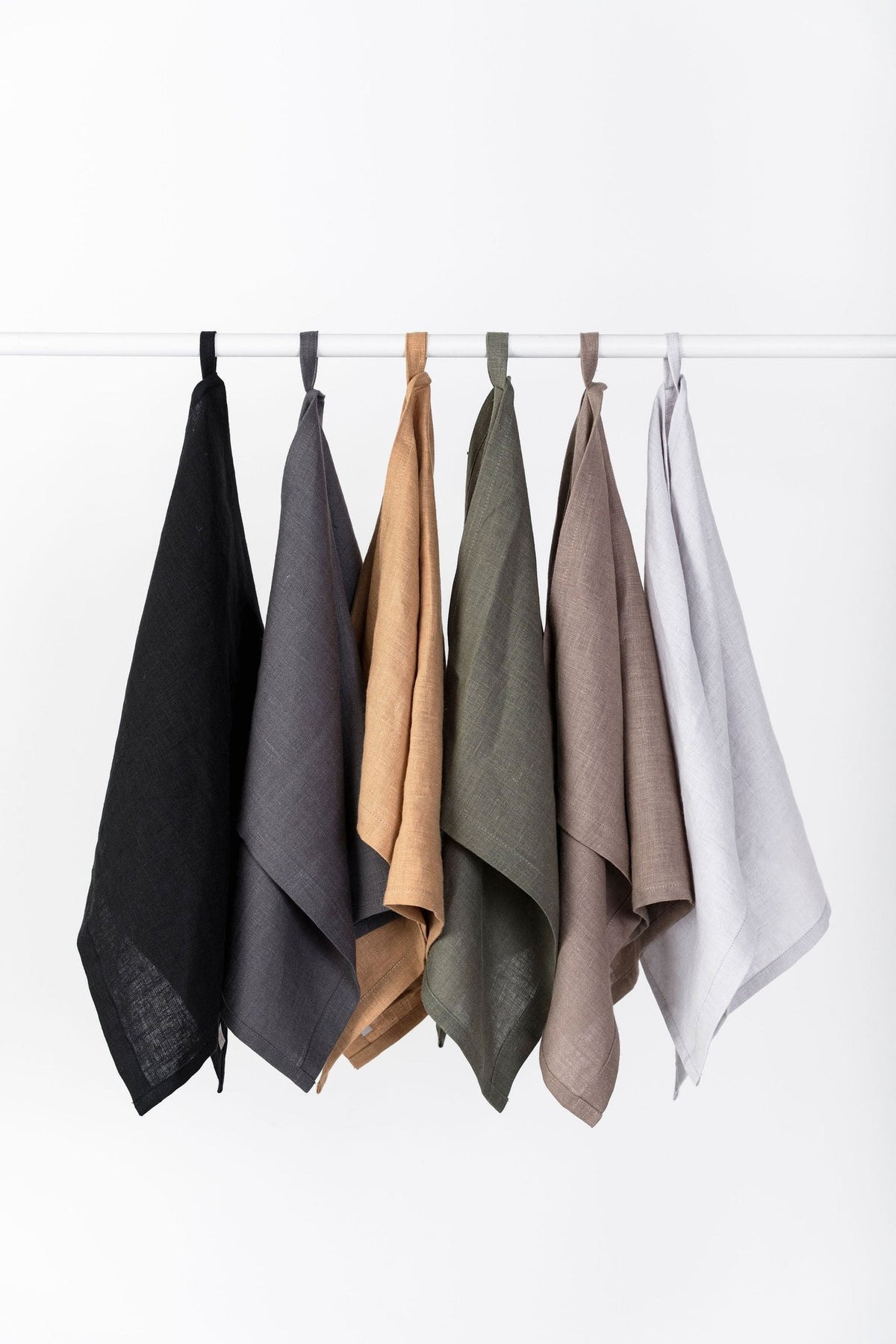 1. Set of six linen kitchen towels in black, gray, caramel, olive, cappuccino, and light gray hanging on a rod