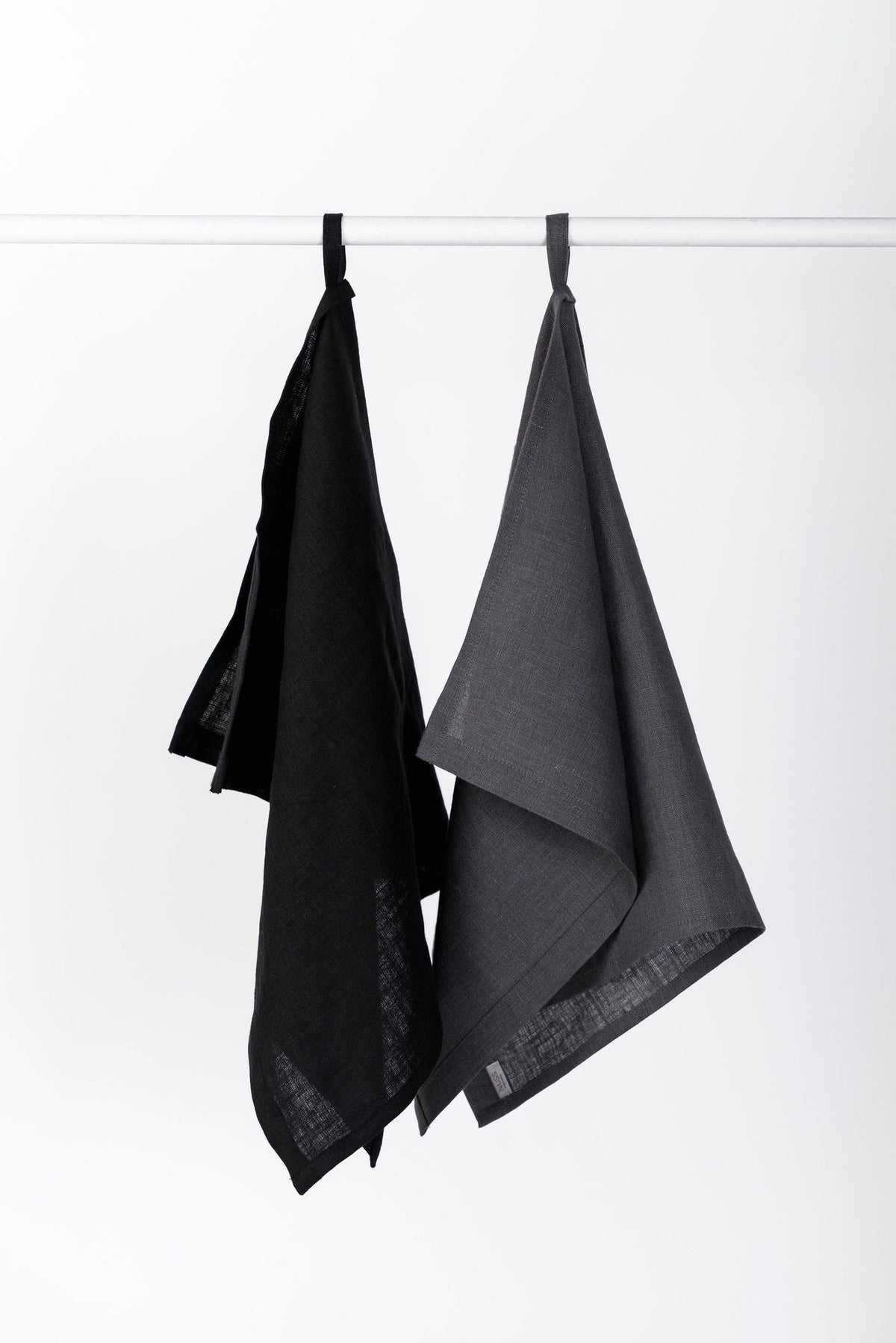 6. Two linen kitchen towels in black and gray hanging on a rod