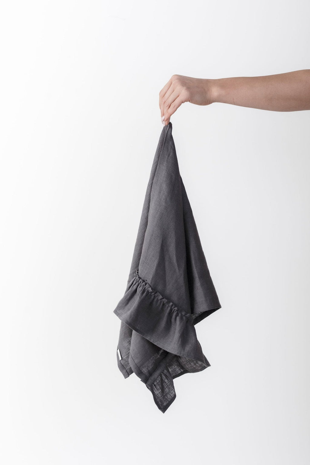 3. Hand holding a gray linen kitchen towel with ruffles against a white background