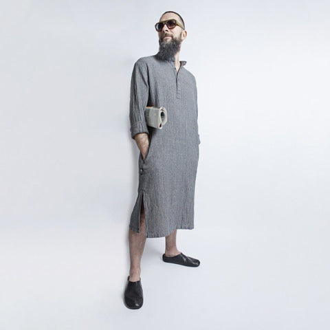 1. Man wearing KOOSdisain black and gray fishbone pattern linen dress with large pockets, standing confidently in studio setting