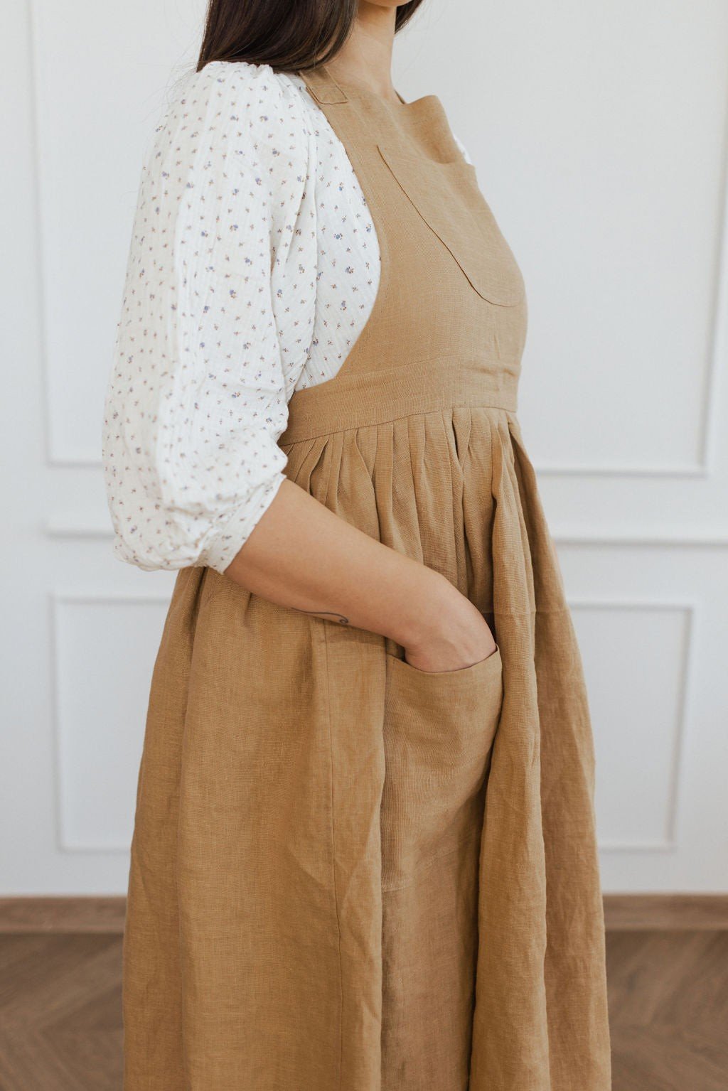 3. Side view of brown linen apron with pocket detail and white blouse