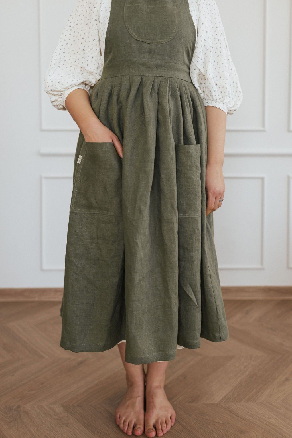 17. Front view of green linen apron with hand in pocket