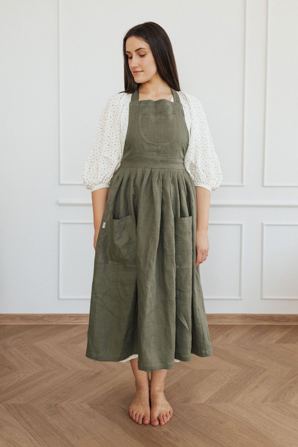 5. Woman in green linen apron with pockets standing in a bright room