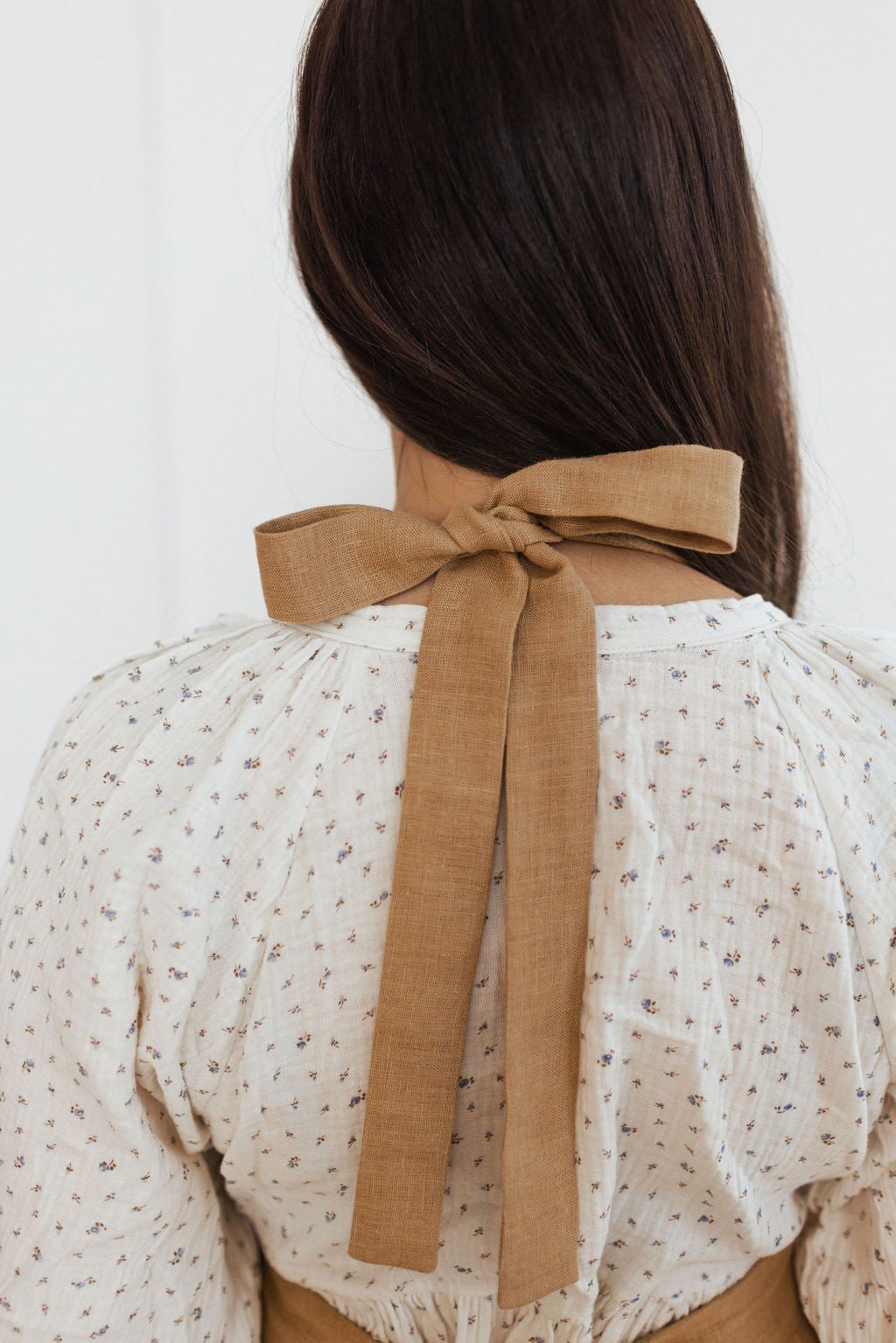 8. Back view of brown linen apron with bow-tied straps