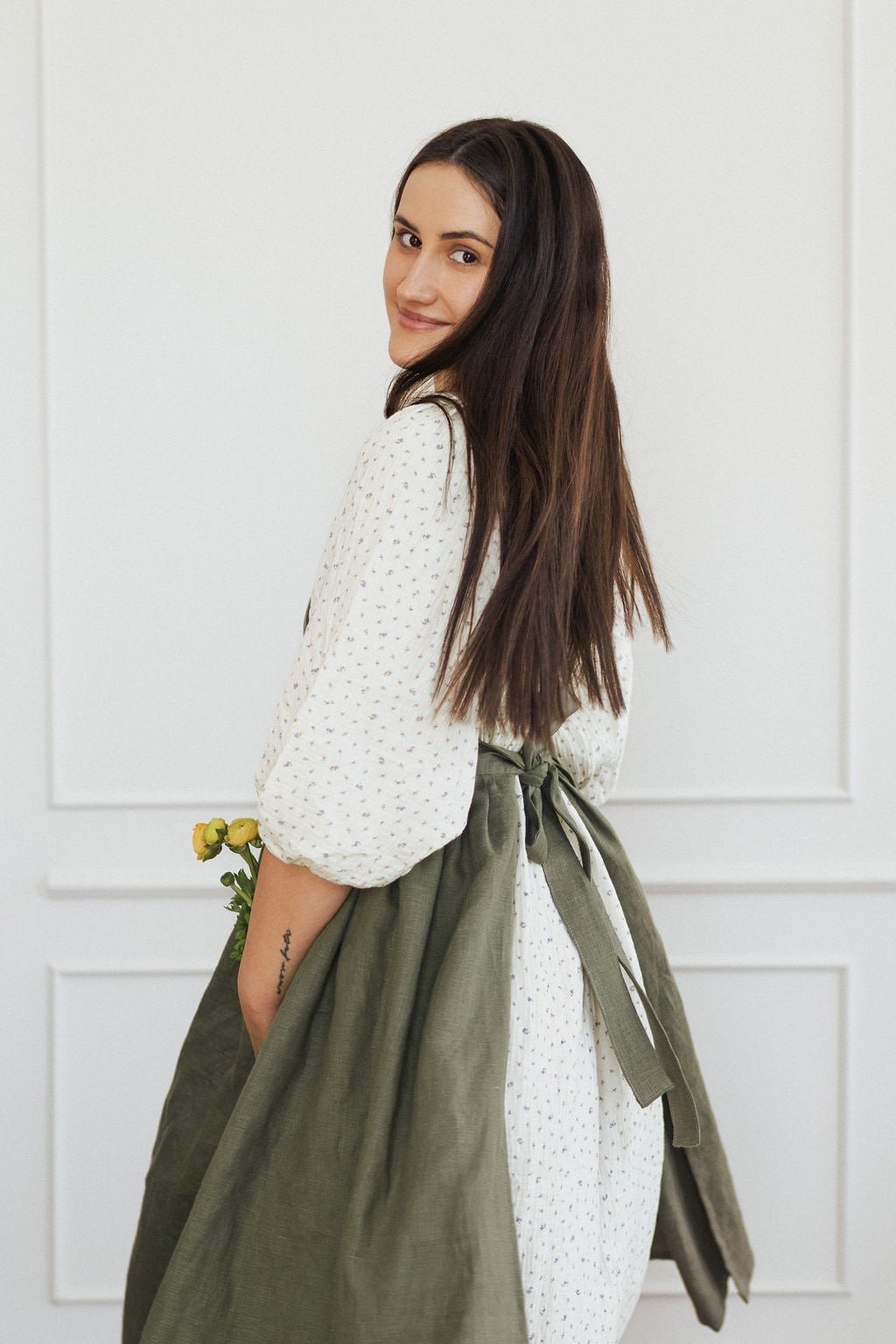 18. Woman in green linen apron with long hair holding flowers