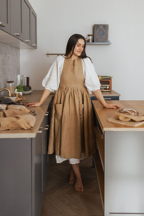 1. Woman wearing brown linen retro apron with pockets in a kitchen setting