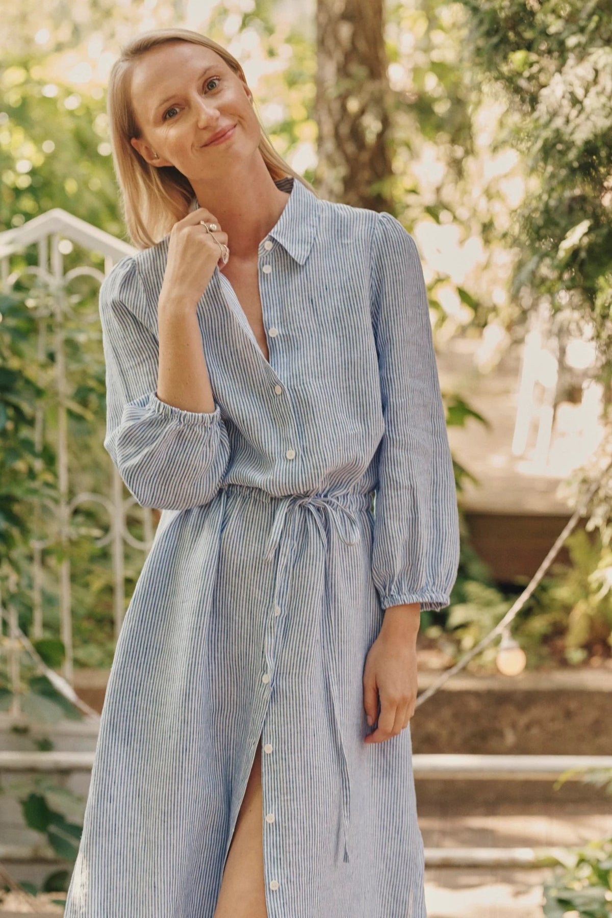 4. Close-up of woman in blue and white striped linen dress with button fastening and drawstring belt, smiling outdoors