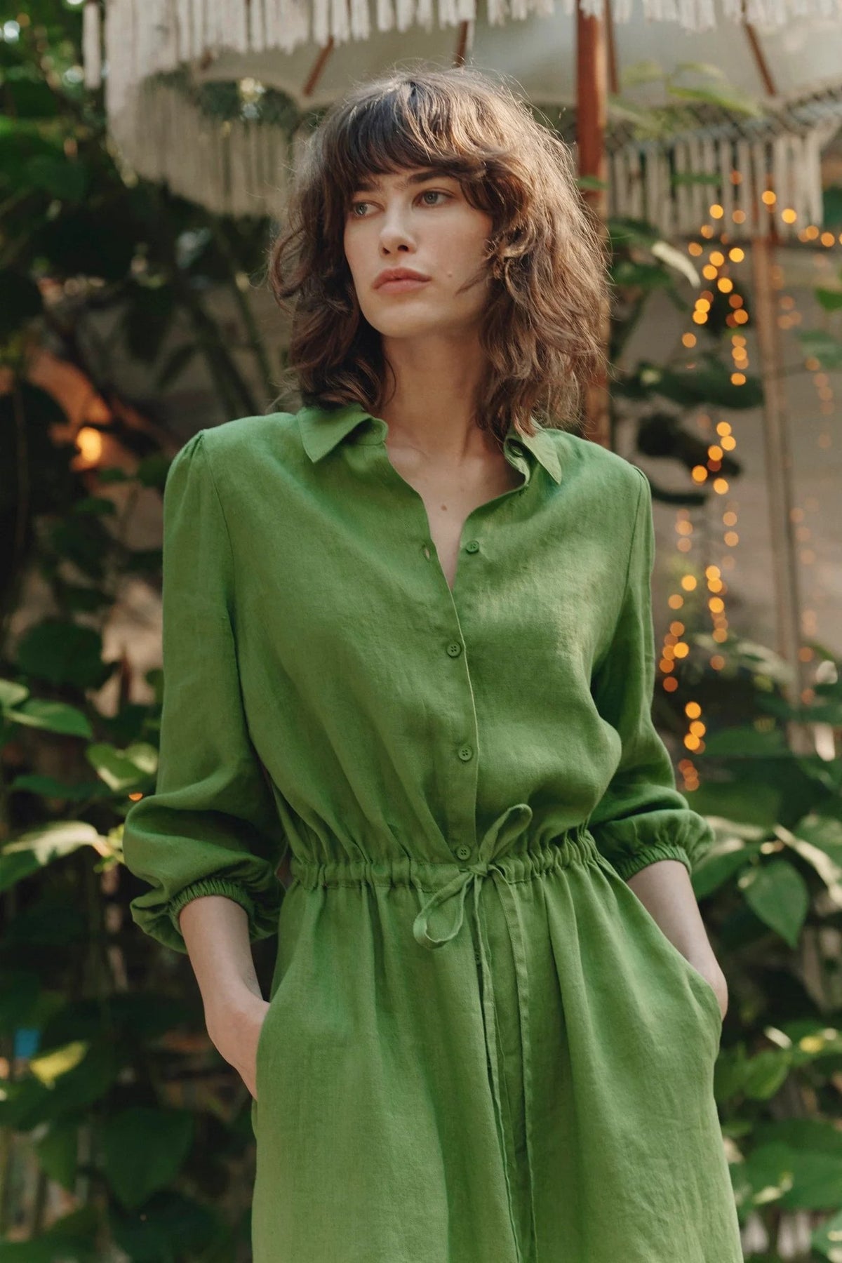 3. Close-up of woman wearing green linen long shirt dress with button closure and drawstring belt, in garden setting