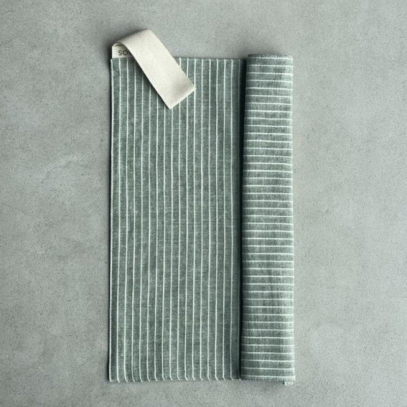 5. Linen sauna seat cover rolled partially, displaying light striped pattern and cotton hook on grey background.