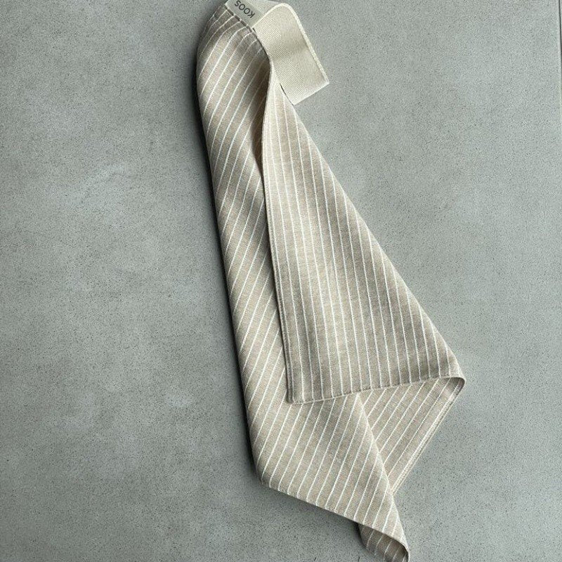 10. Linen sauna seat cover draped with light stripes and cotton hook, highlighting soft texture and design.