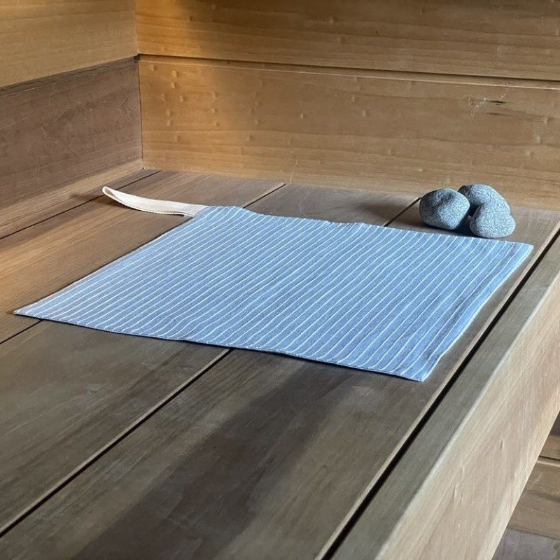 11. Single linen sauna seat cover with light stripes on wooden sauna platform, featuring cotton hook and soft texture.