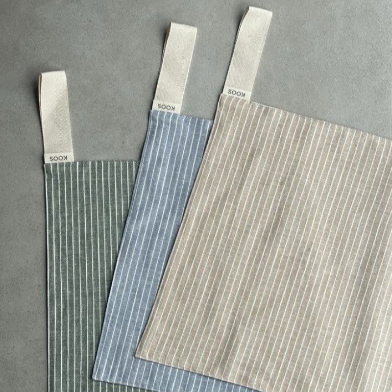 4. Flat lay of three linen sauna seat covers in different colors with light stripes and cotton hooks, showing design variety.